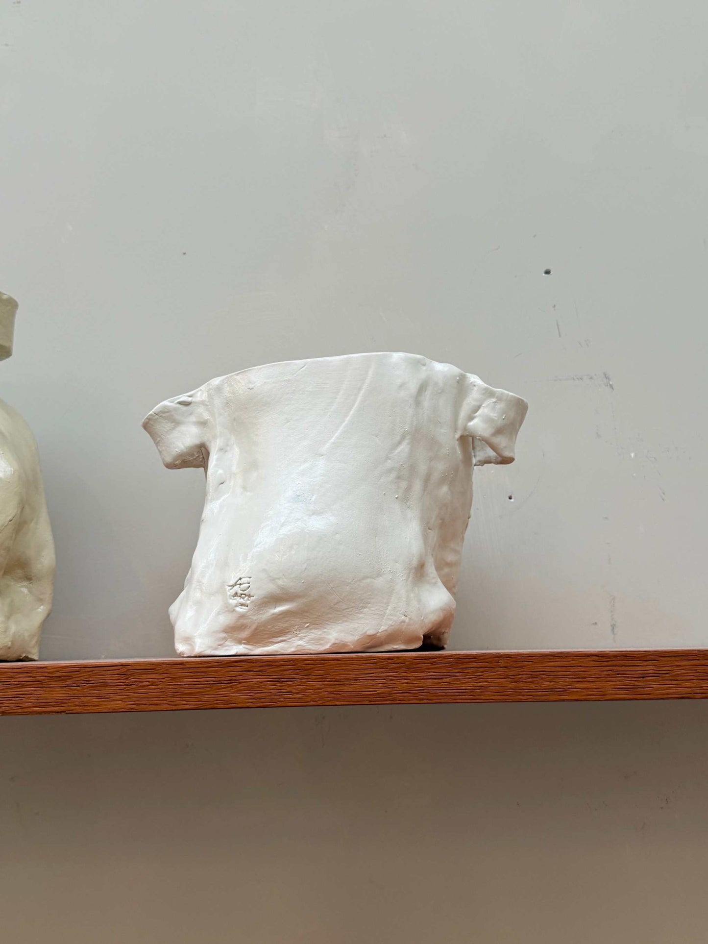 Handcrafted white ceramic vase with unique irregular form displayed on wooden shelf ceramic vase object 03