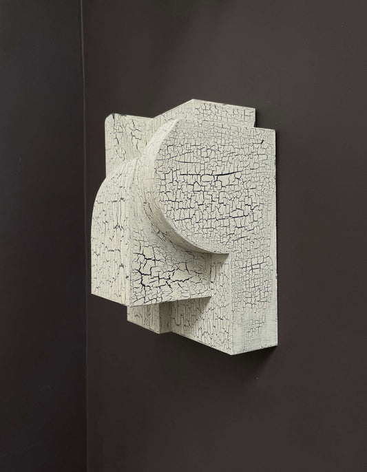 Bep Sculpture with crackle finish mounted on a black wall.