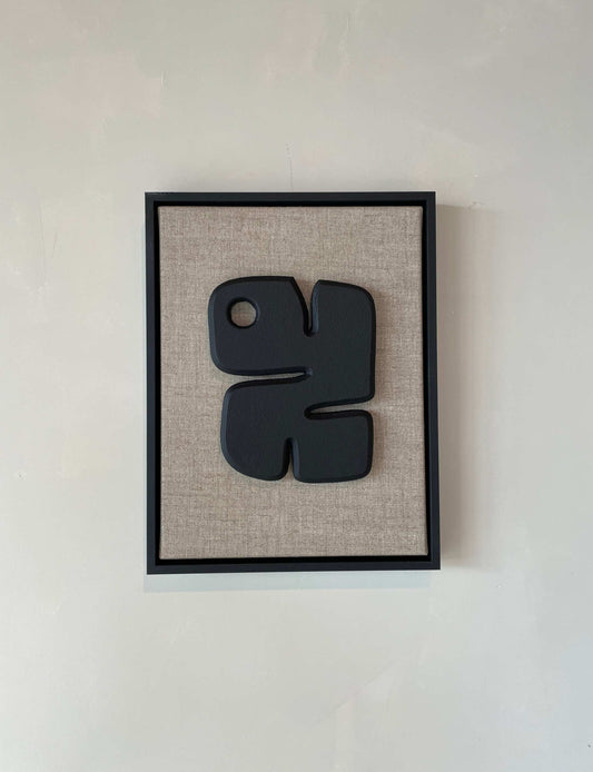 Canvas Noa artwork with anthracite black frame and textured plaster finish on a beige background.