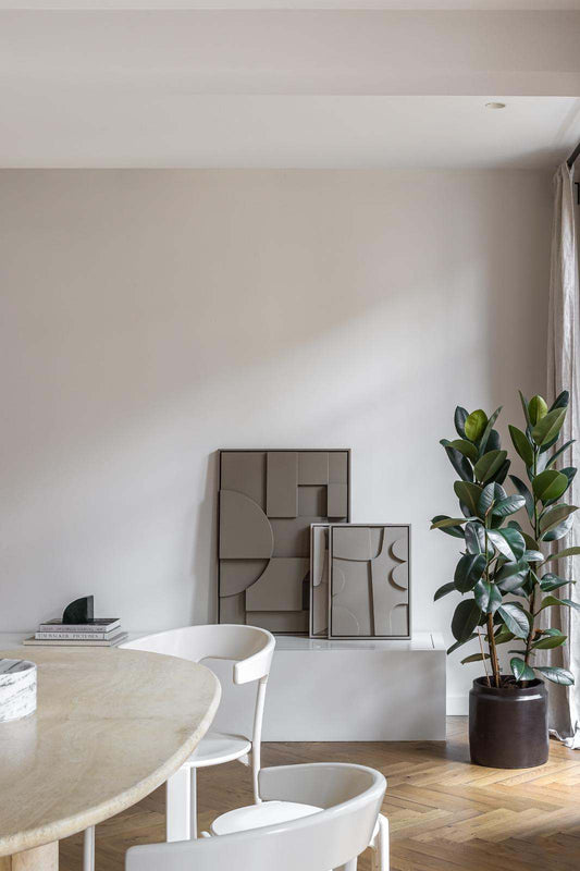 Modern interior with '#21.22 Georgia' art pieces made from eco-friendly materials, featuring geometric designs, placed against a neutral wall beside a potted plant.