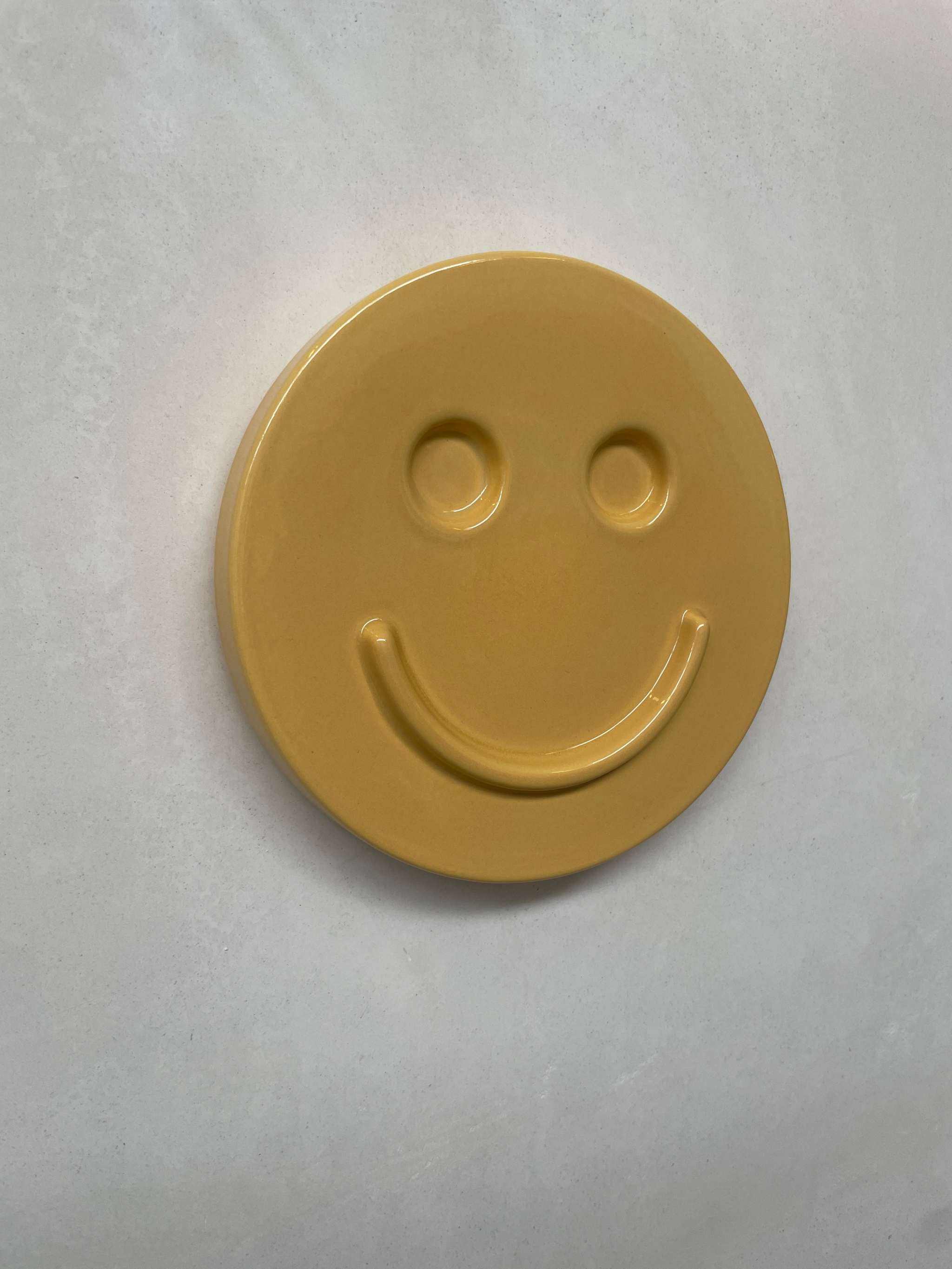 Yellow HAPPY ceramic artwork with smiley face design, handcrafted by Edith Beurskens.