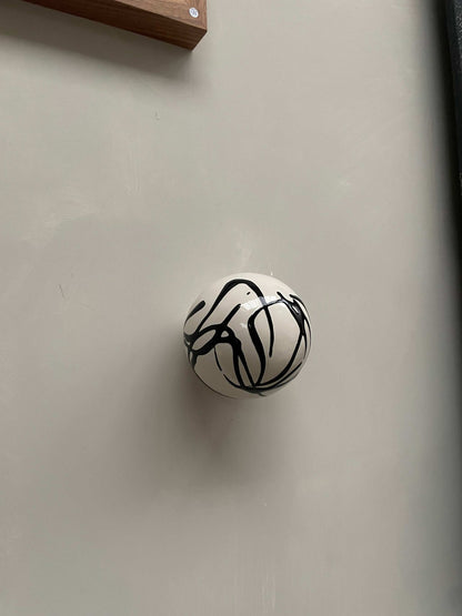 Handcrafted ceramic ball wall sculpture with artsy swirl design.