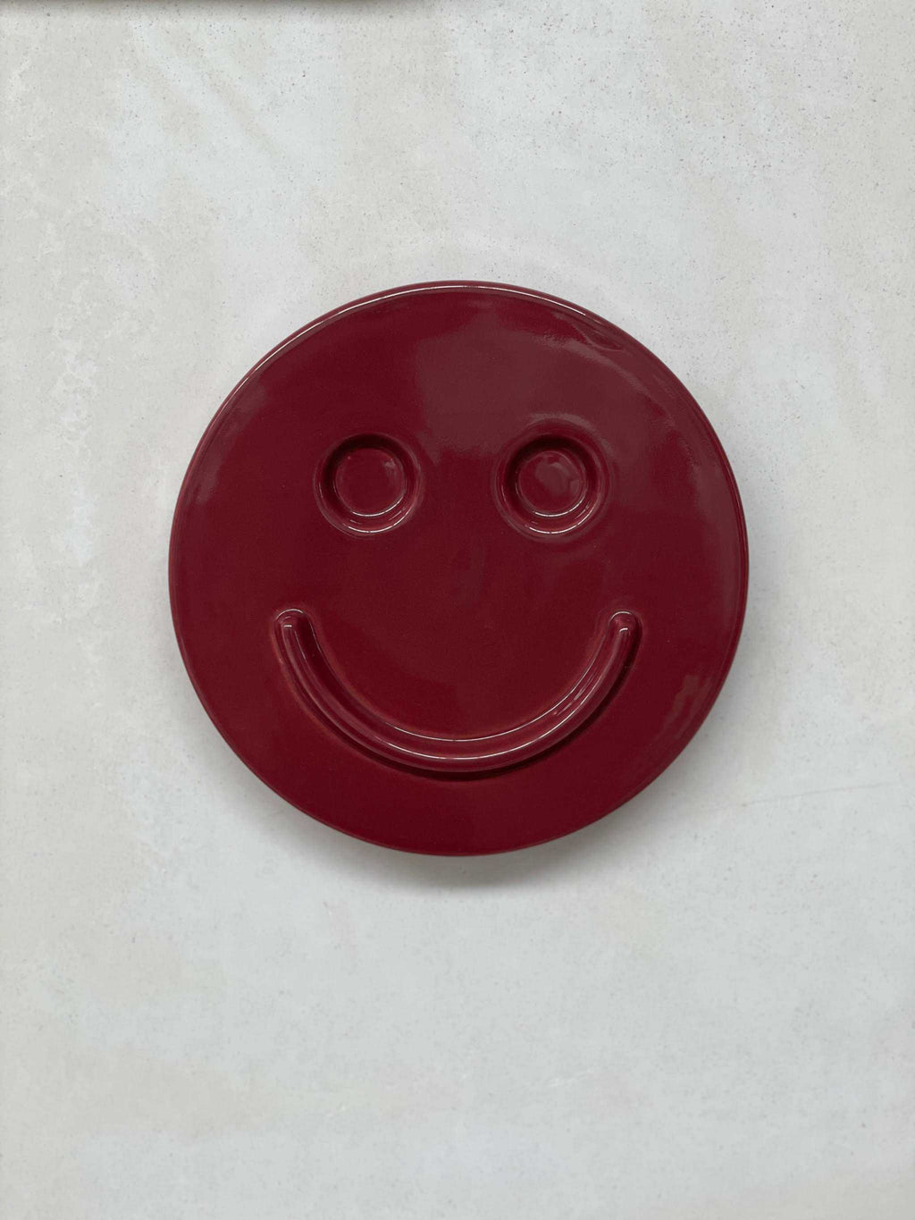 Burgundy ceramic smiley face artwork by Edith Beurskens, handcrafted at Royal Goedewaagen.
