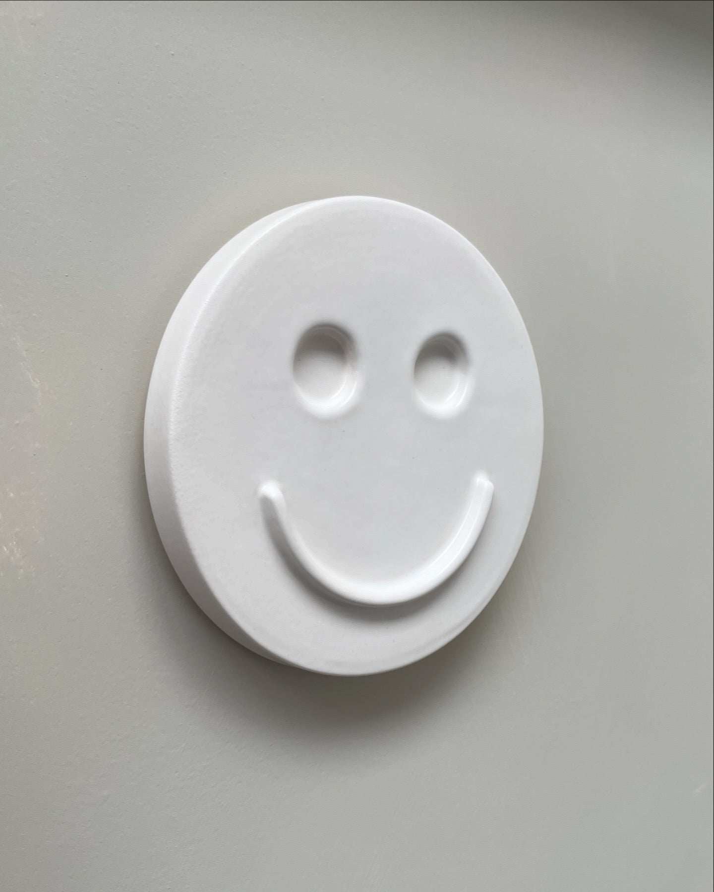 white ceramic wall art with smiley face handcrafted by Edith Beurskens