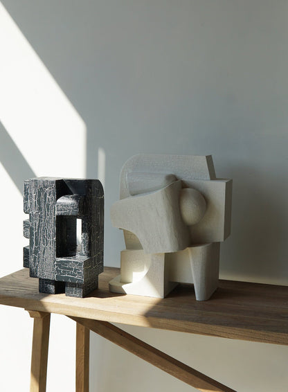 Sculpture with organic form and crackle finish on a wooden table, featuring architectural elegance inspired by female pioneers.