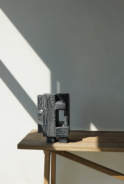 Odile sculpture in organic form with crackle finish placed on a wooden table.