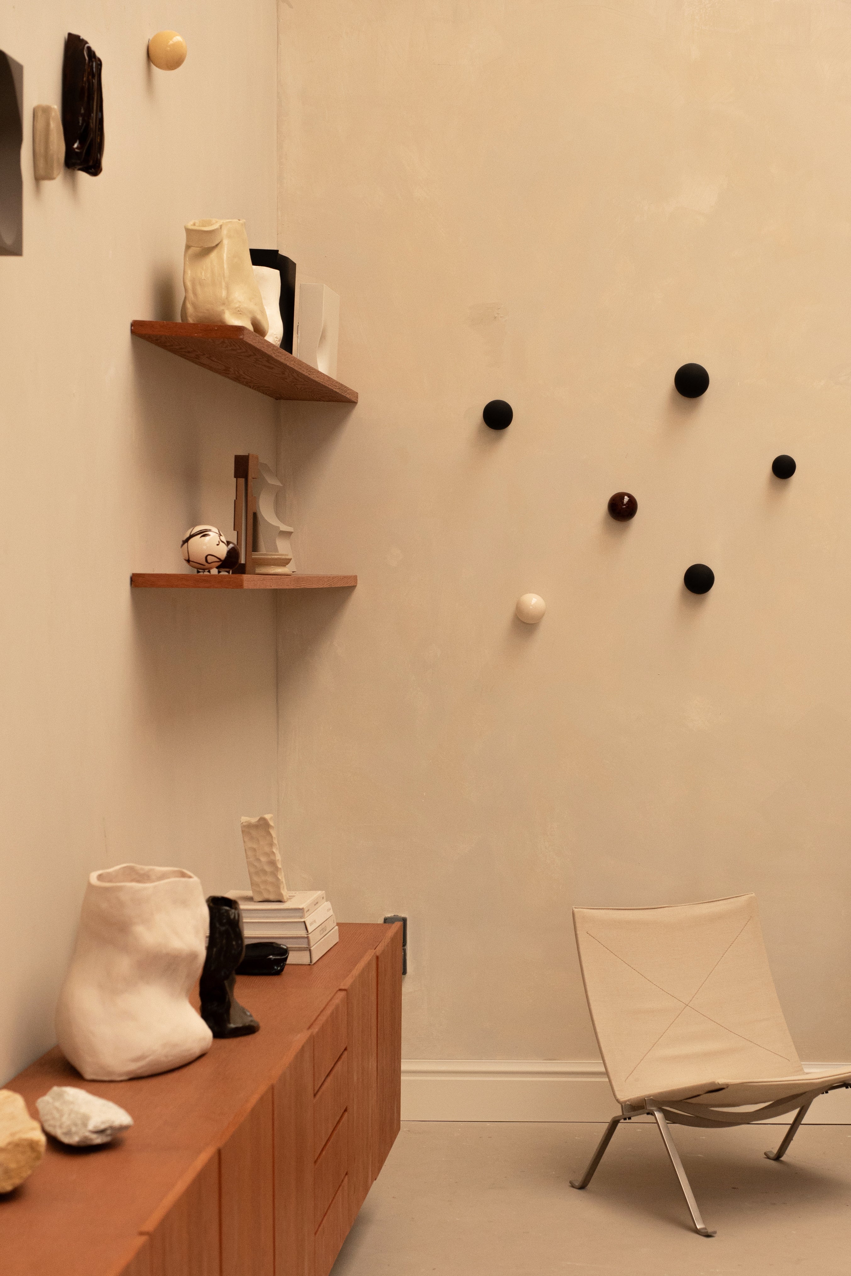Handcrafted unique ceramic vase object displayed on wooden cabinet in minimalist room with shelves and chair