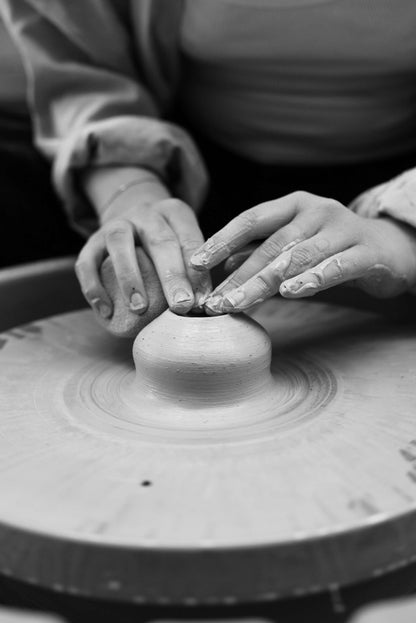 Private throwing wheel lesson in progress, hands shaping clay on pottery wheel.
