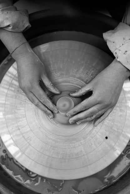 Hands shaping clay on a pottery wheel during a private throwing wheel lesson.