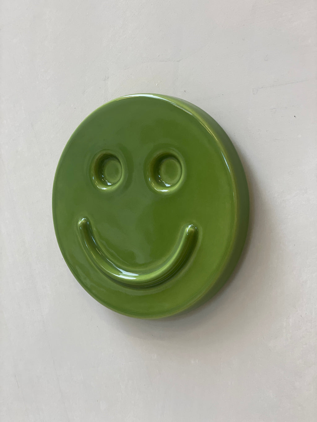 Green 'HAPPY' ceramic artwork by Edith Beurskens, handcrafted smiley face.