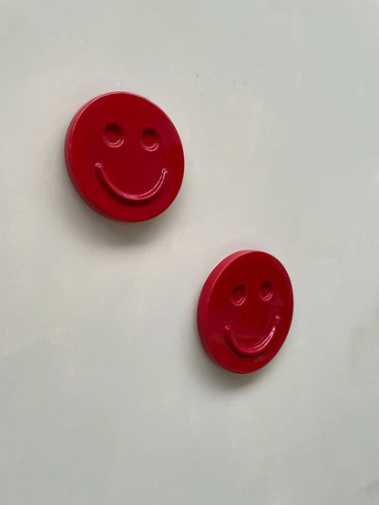 Red HAPPY ceramic wall art smiley faces mounted on white wall