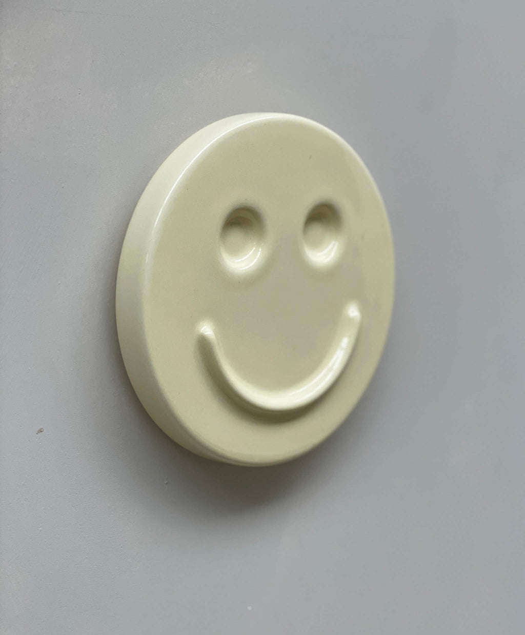 Ceramic artwork with smiley face design, titled "Butter 'HAPPY'," handcrafted by designer Edith Beurskens.
