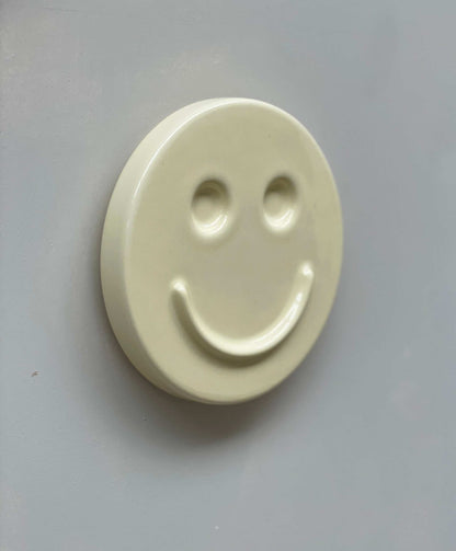Ceramic artwork with smiley face design, titled "Butter 'HAPPY'," handcrafted by designer Edith Beurskens.