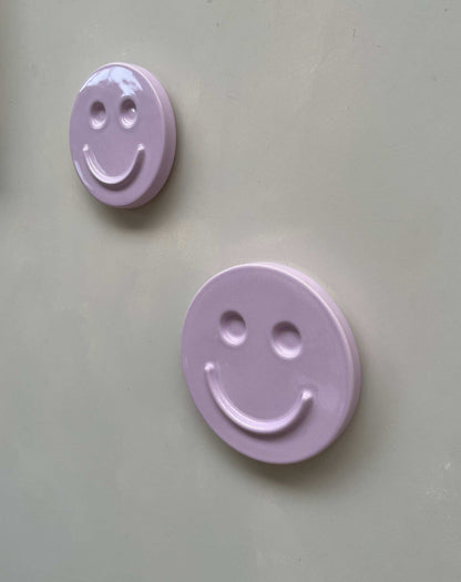 Orchid 'HAPPY' ceramic artwork with smiling faces on a beige background.