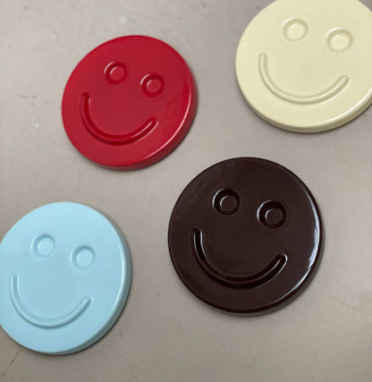 Smiling ceramic artwork with various colors including red, cream, blue, and brown.