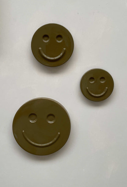 Olive 'HAPPY' ceramic artwork with smiley faces in varying sizes.
