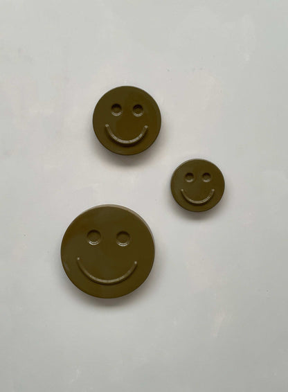 Olive 'HAPPY' ceramic smiley face artwork trio on white background.