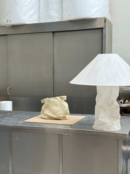 Handcrafted unique ceramic vase object with textured surface displayed on metal table next to white sculptural lamp