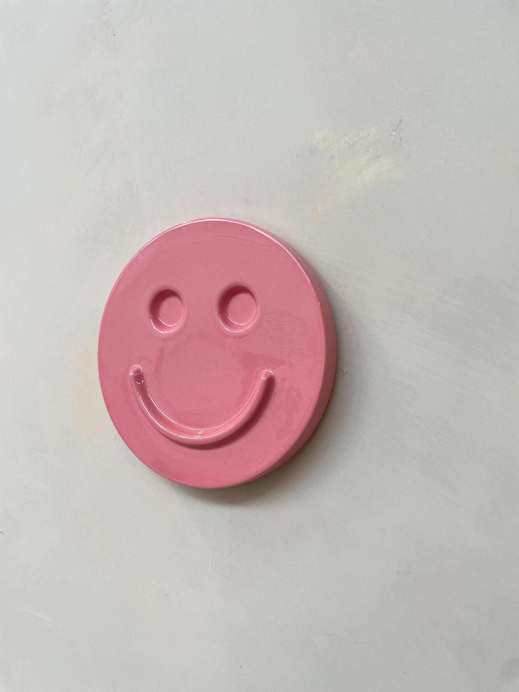 Pink ceramic artwork with smiley face design by Edith Beurskens.