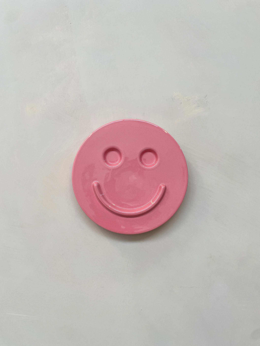 Pink ceramic smiley face artwork titled "HAPPY" by Edith Beurskens.