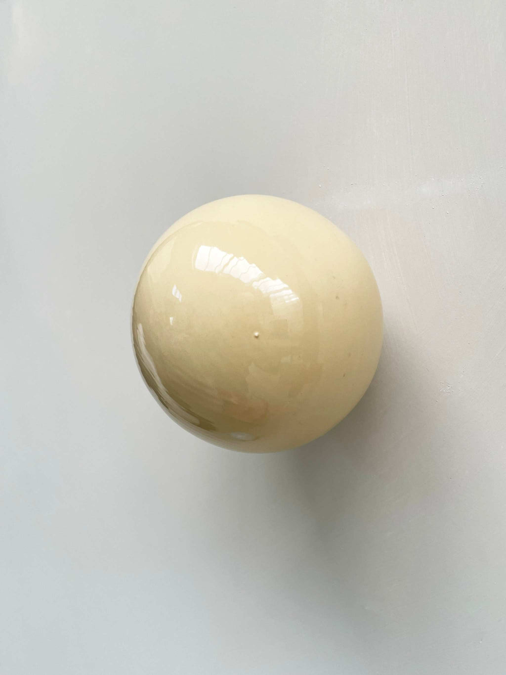 Handcrafted ceramic ball wall sculpture in butter color.
