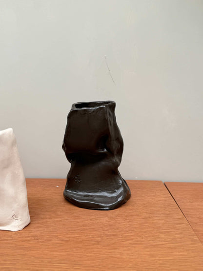 Handcrafted unique black ceramic vase object 02 with irregular shape on wooden surface
