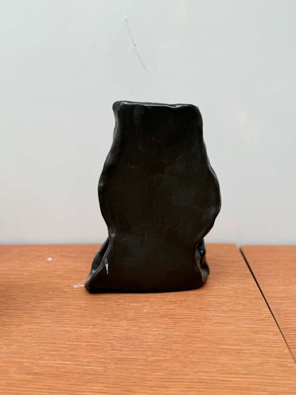 Handcrafted black ceramic vase object 02 with irregular shape on wooden surface