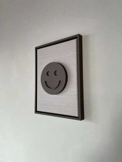 Canvas Happy artwork with dark frame, biodegradable PLA base, and structured plaster finish.