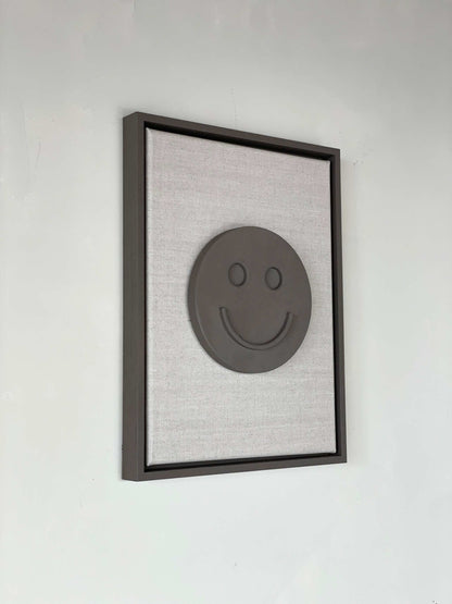 Canvas Happy artwork with smiley face, biodegradable PLA base, structured plaster finish, framed.