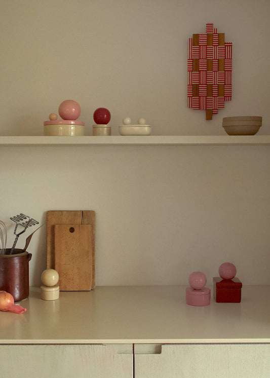 Ceramic box 'BOULE' in square shape, sorbet cherry color, displayed on a shelf with decorative items.