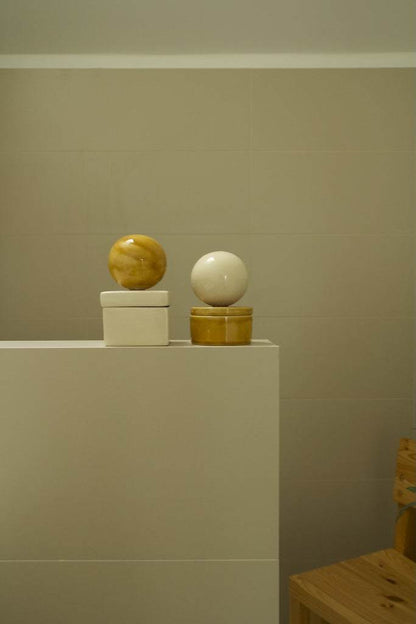 Ceramic box 'BOULE' SQUARE Cognac Vanilla displayed with sphere lid on modern surface.