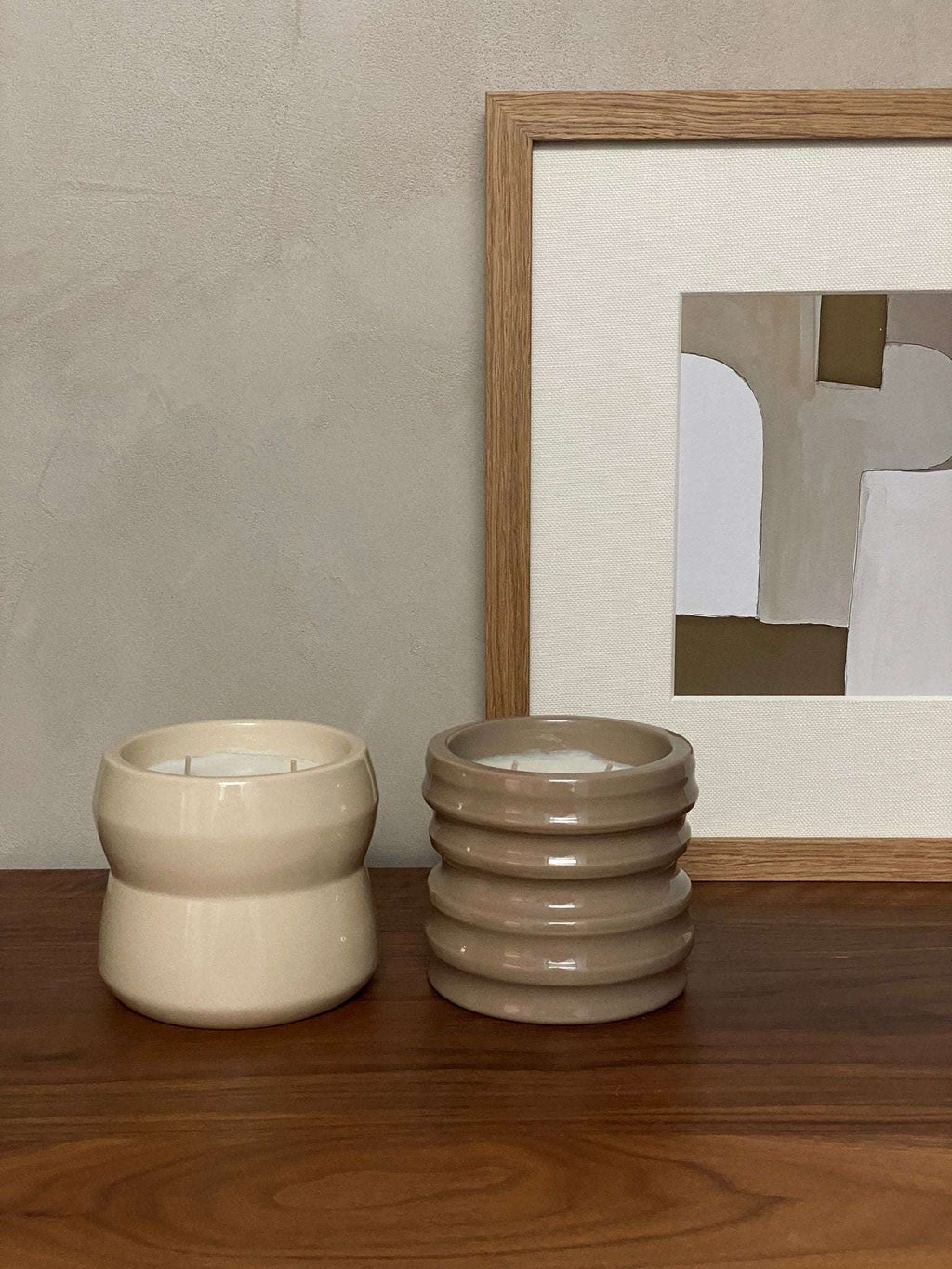 Shape 02.01 Chalk scented candles, ceramic holders on wooden table, abstract painting in background.