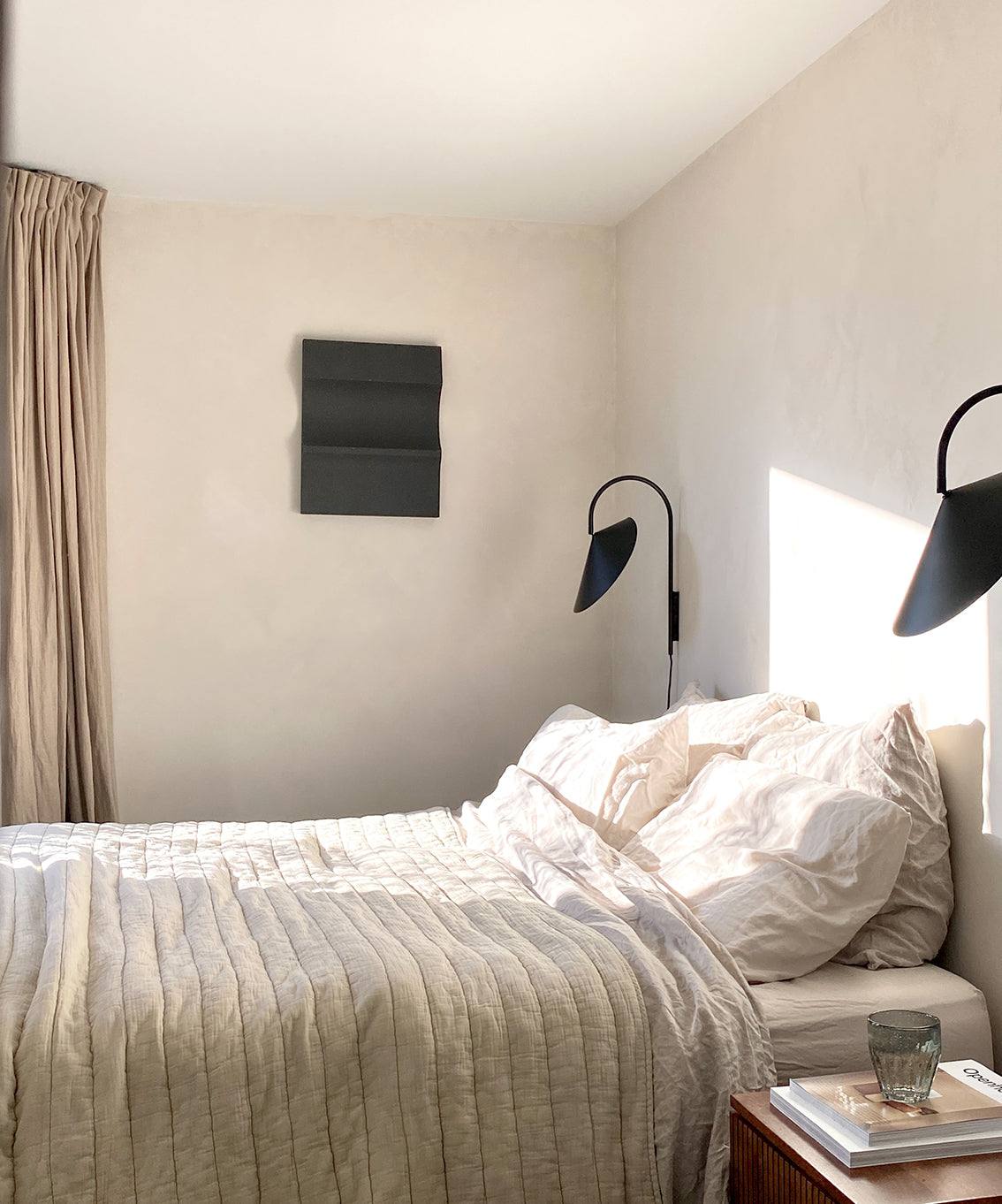 3D art piece on wall in minimalist bedroom setting.