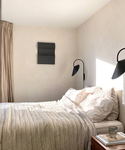 3D art piece on wall in minimalist bedroom setting.