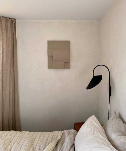 Modern art shapes wall piece in neutral tones in bedroom setting.
