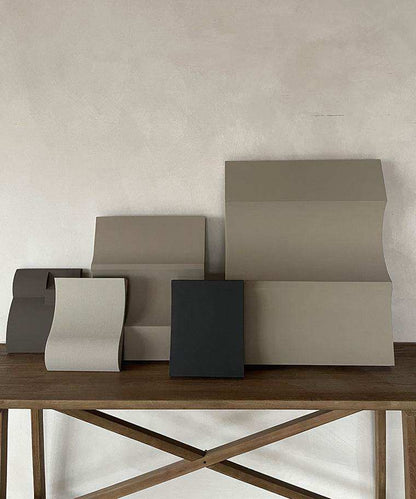 Sculptural artwork pieces made from biodegradable PLA with sand texture and eco-paint finish on a wooden table.