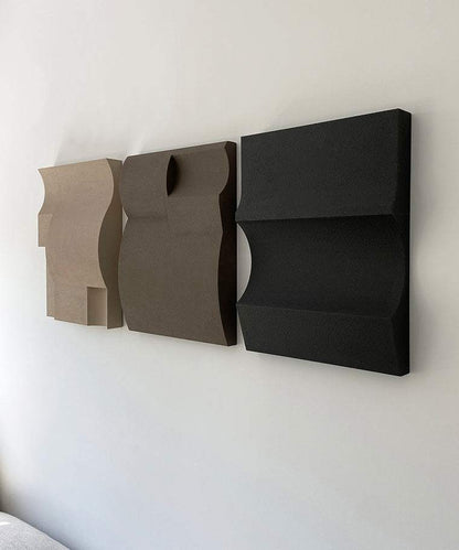 Handmade 3D art panels in neutral tones displayed on a wall.