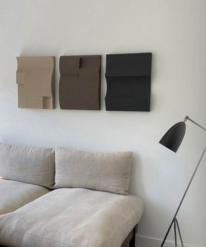 Handmade art pieces on wall above couch with unique textures and eco-paint finish.