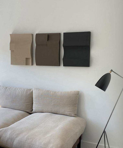 Modern art shapes wall decor in Dark Fog, Attic, and Anthracite shades above a beige sofa.