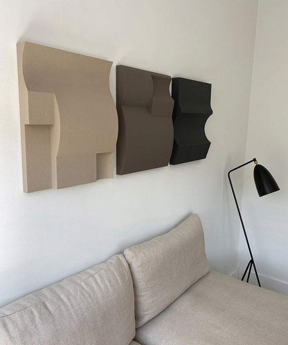 Hand-made 3D art pieces on wall above a couch, made of plant-based PLA with sand texture and eco-paint.