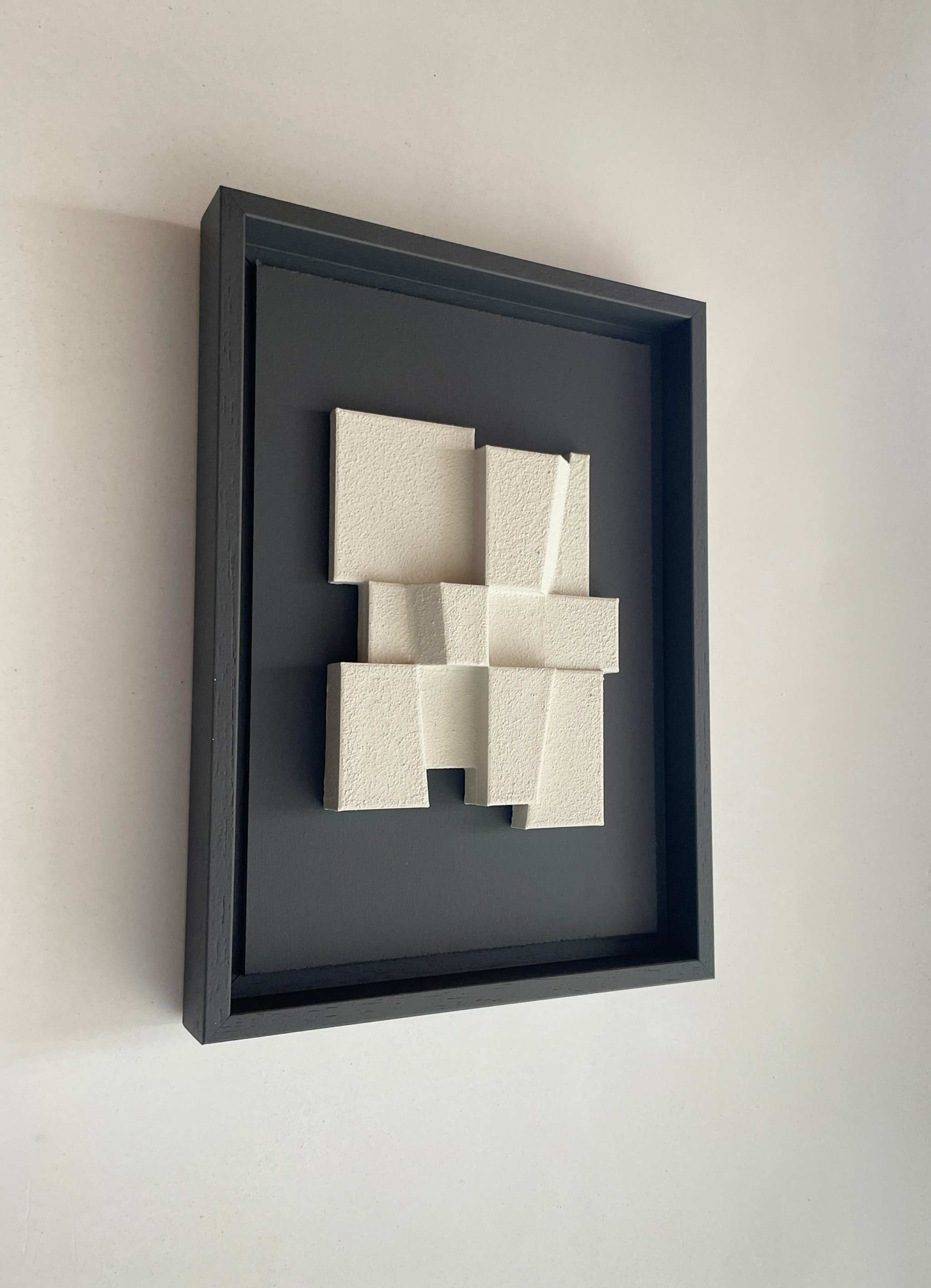 Hand-made 23.2 Deda artwork with textured white design in black frame, made from biodegradable PLA.