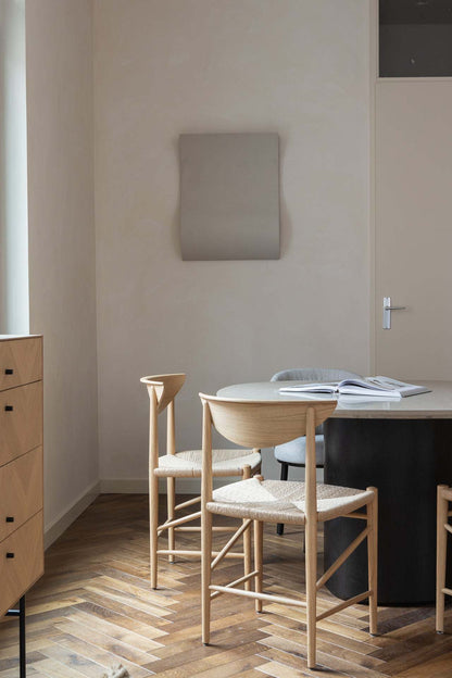 Modern minimalist interior featuring '22.08 Heat' artwork on wall, natural wood furniture, and parquet flooring.