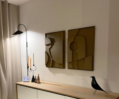 Contemporary art pieces on a wall next to minimalist decor, featuring geometric designs in a modern interior setting.